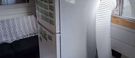 A compact kitchen with a refrigerator, a window with a view, and a heater.