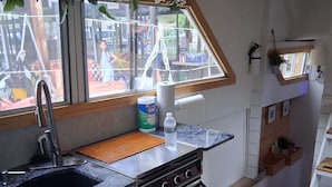 A compact kitchen with a window, a sink, a stove, and a countertop.