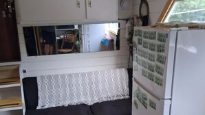 A compact kitchen with a built-in bench, a refrigerator with magnets, and a window providing natural light.
