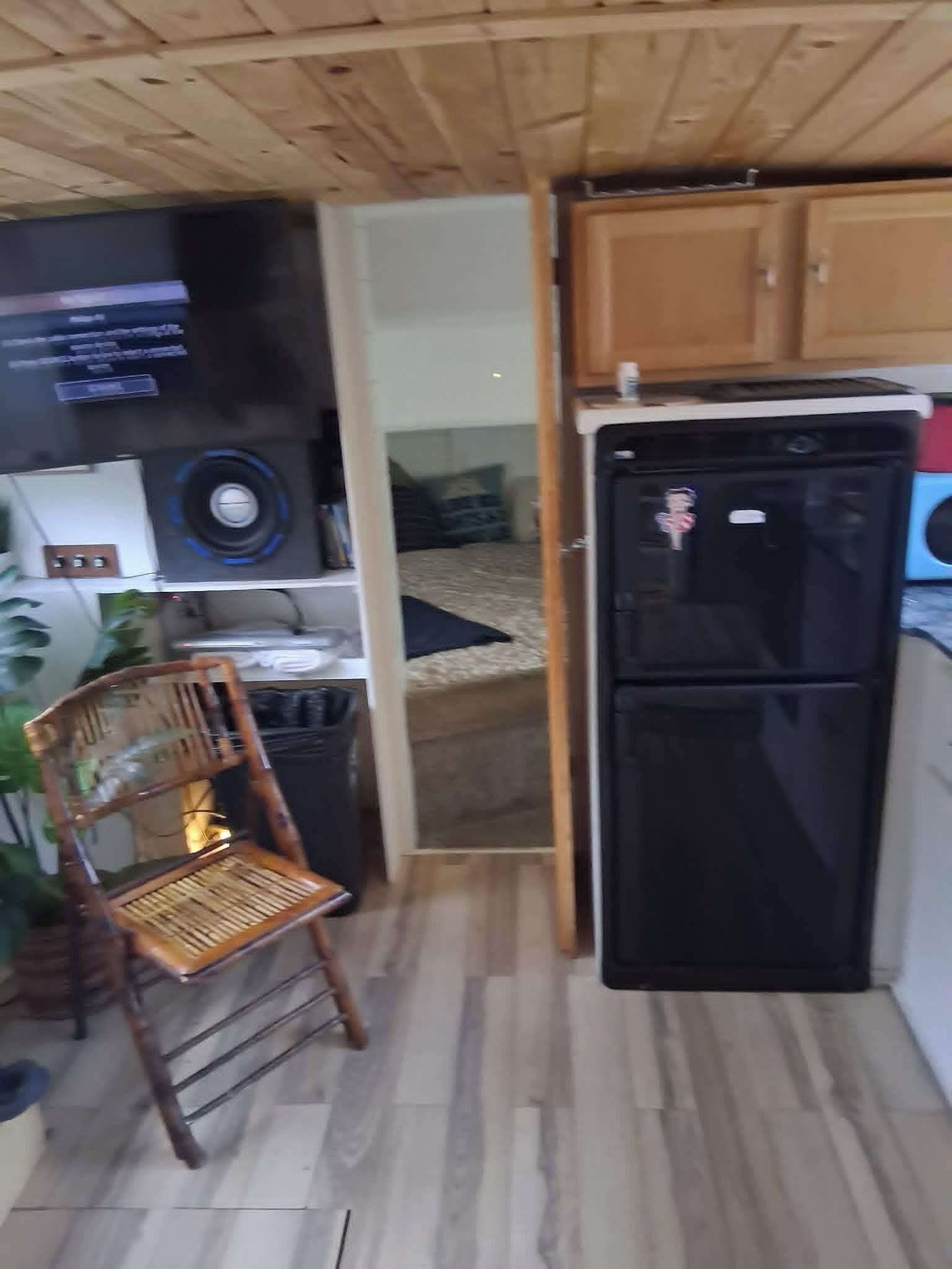 Une cuisine de taille réduite avec un réfrigérateur noir, un meuble en bois et une chaise.