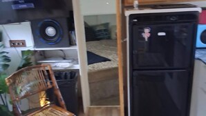 A compact kitchen with a black refrigerator, a wooden cabinet, and a chair.