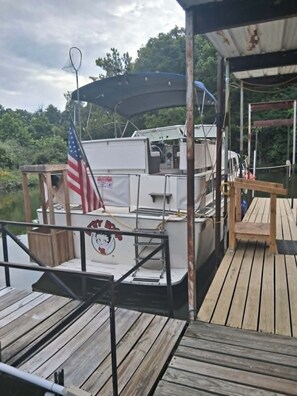 A boat docked at a wooden pier with an American flag, a covered area, and a small table.