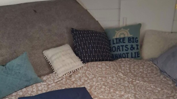 A bed with a patterned bedspread, a folded blanket, and several pillows.