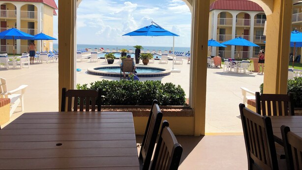 A poolside area with lounge chairs and umbrellas, a pool, and a view of the beach. - Beautiful condo ocean view. (New Smyrna Beach)