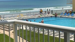 A pool area with a view of the ocean, a fenced deck, and lounge chairs. - Beautiful condo ocean view. (New Smyrna Beach)