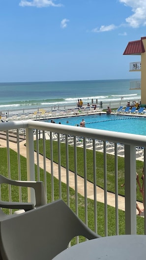A pool area with a view of the ocean, a fenced deck, and lounge chairs. - Beautiful condo ocean view. (New Smyrna Beach)