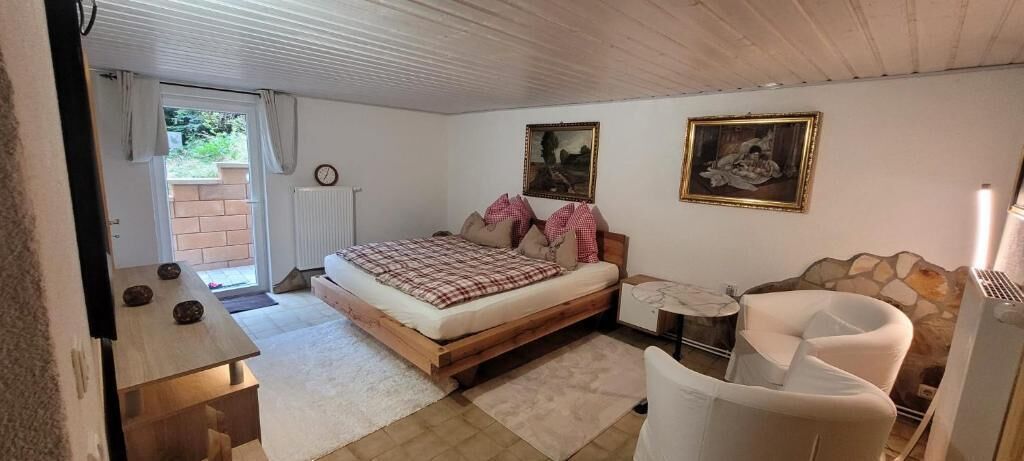 Un dormitorio con cama, una silla, una mesita y un radiador.