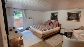 Un dormitorio con cama, una silla, una mesita y un radiador.