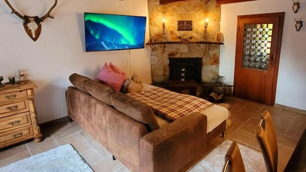 A cozy room with a fireplace, a sofa, and a television displaying the Northern Lights.