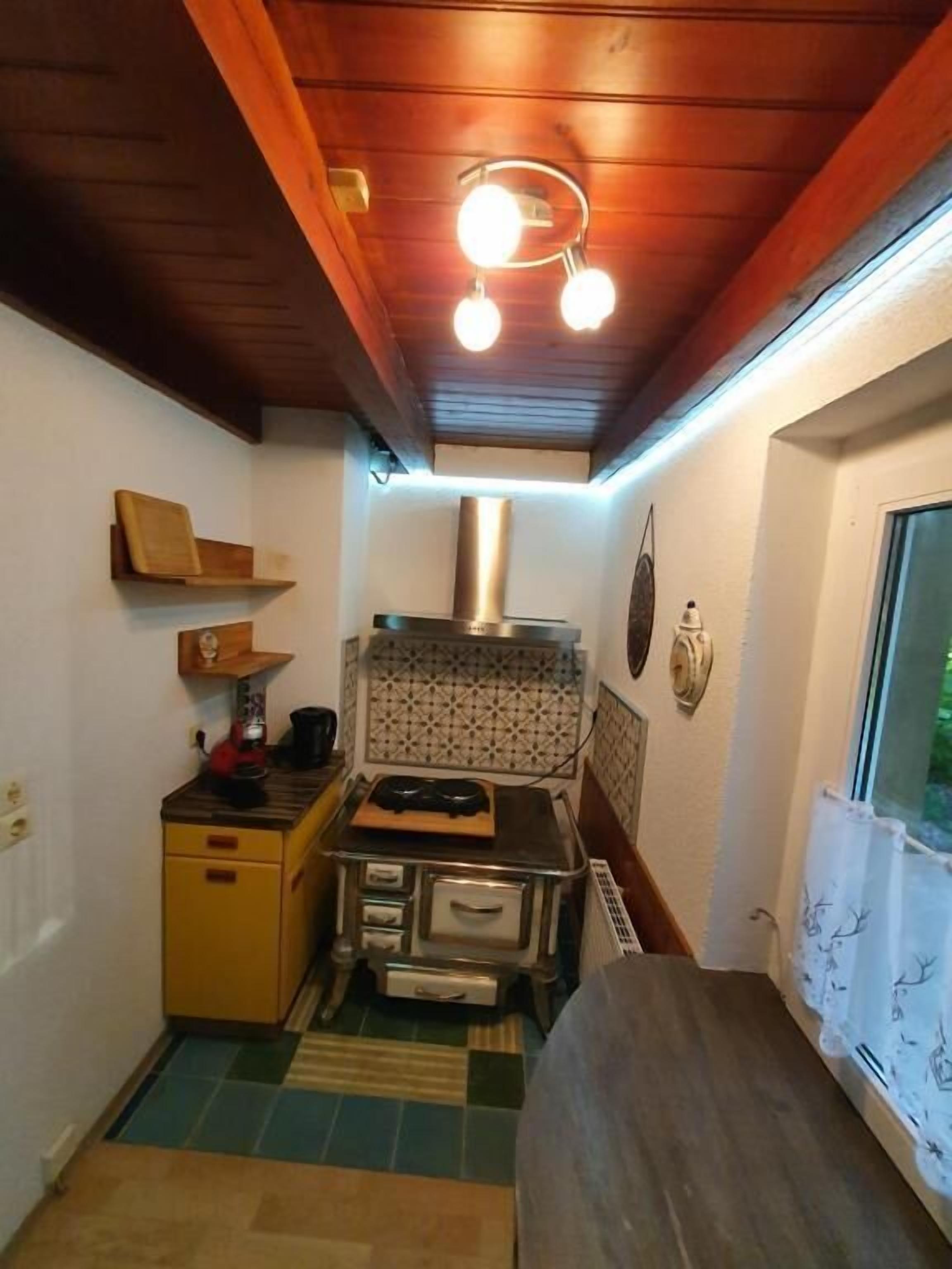 A compact kitchen with a stove, a sink, and a window.