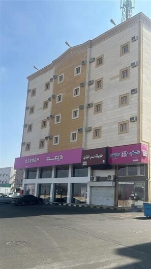 A multi-story building with a commercial ground floor featuring signage in multiple languages.