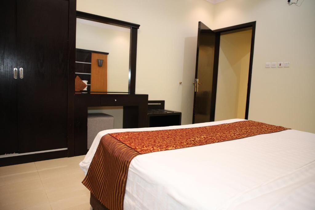 A hotel room with a bed, a wardrobe, a desk, and a mirror.