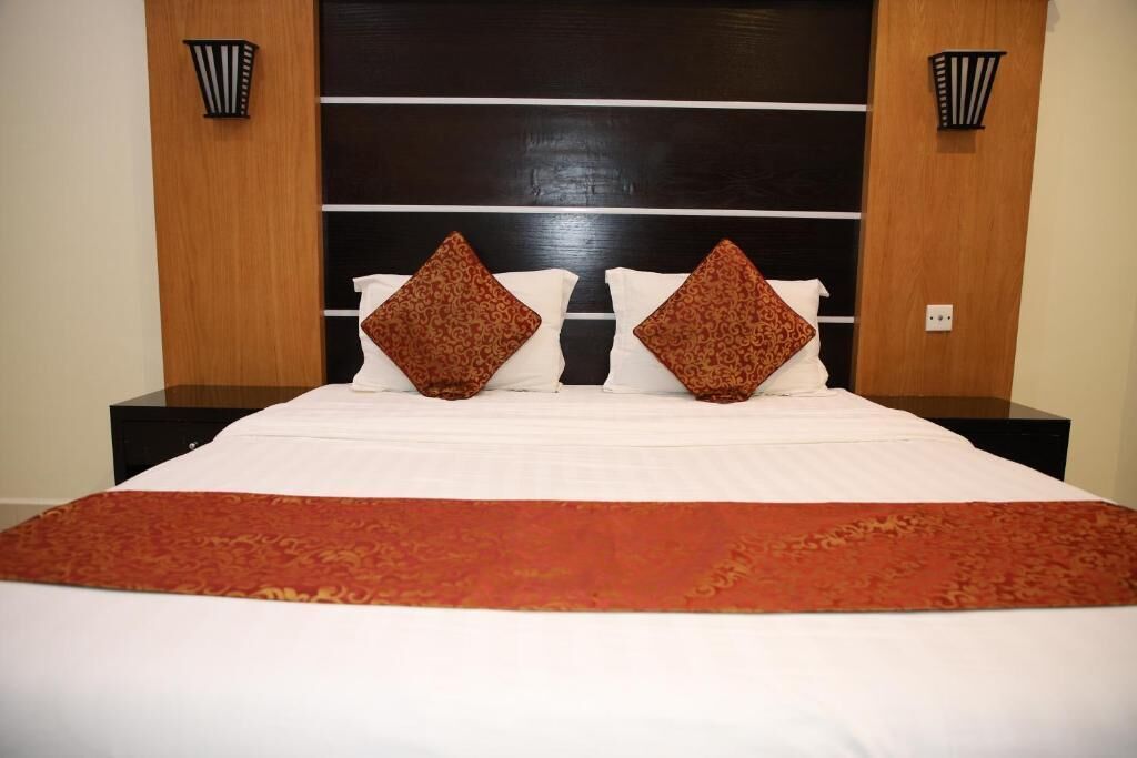 Habitación de hotel con una cama grande, dos mesitas de noche y un cabecero de madera oscura.