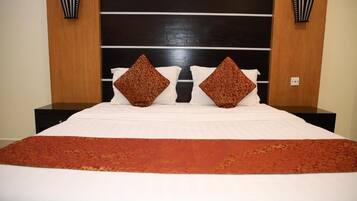 Habitación de hotel con una cama grande, dos mesitas de noche y un cabecero de madera oscura.