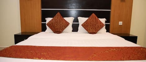 Habitación de hotel con una cama grande, dos mesitas de noche y un cabecero de madera oscura.