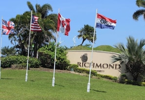 A sign with 'RICHLAND' and multiple flags, including the UK, US, and Canadian flags, with palm trees in the background.