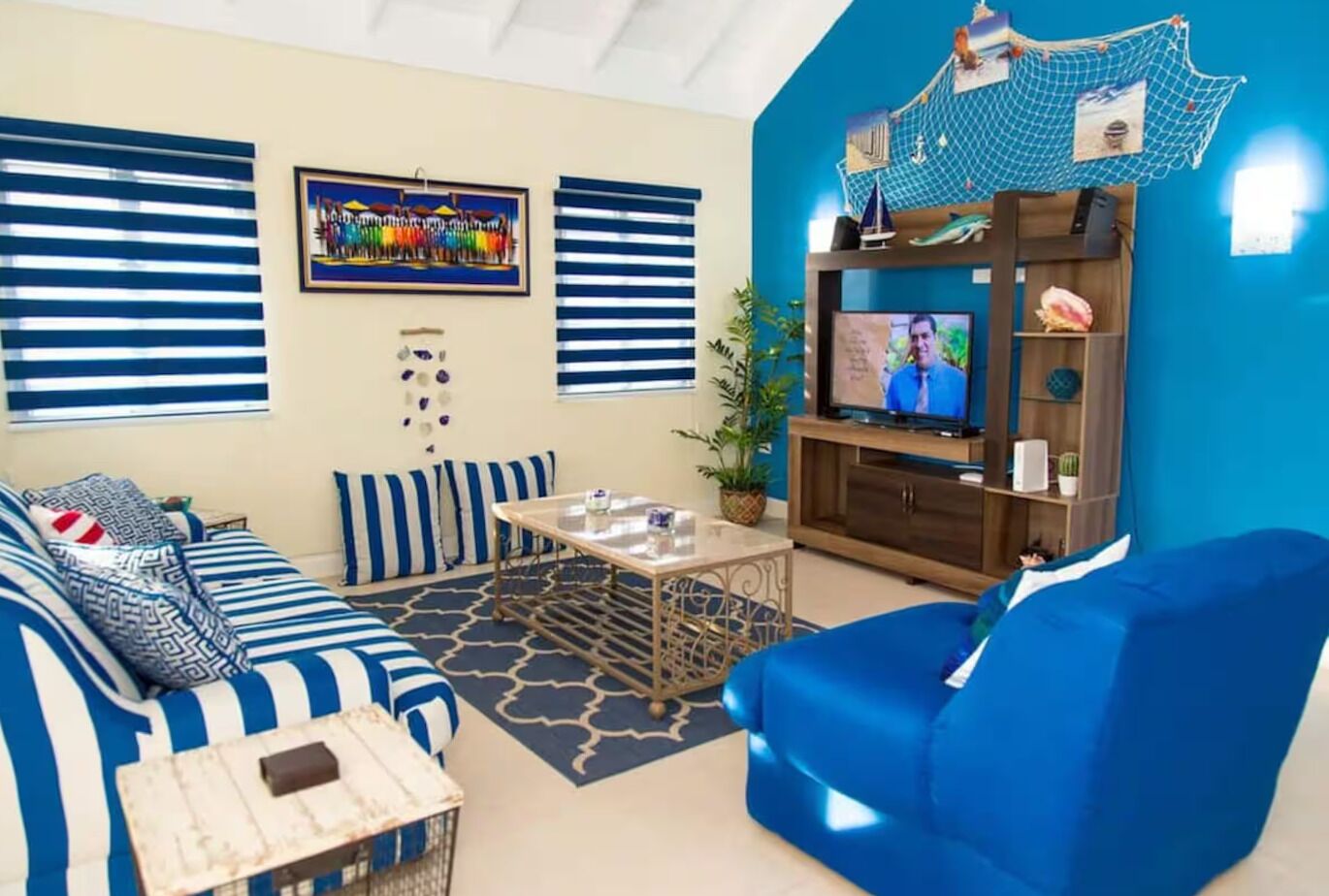 Uma sala de estar com sofá, mesa de centro, televisão e estante de livros.