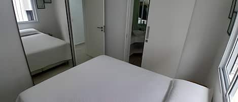 A bedroom with a bed, a wardrobe, and a bathroom visible through an open door.