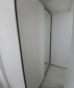 A narrow hallway with a white door and a small, unadorned space at the end.