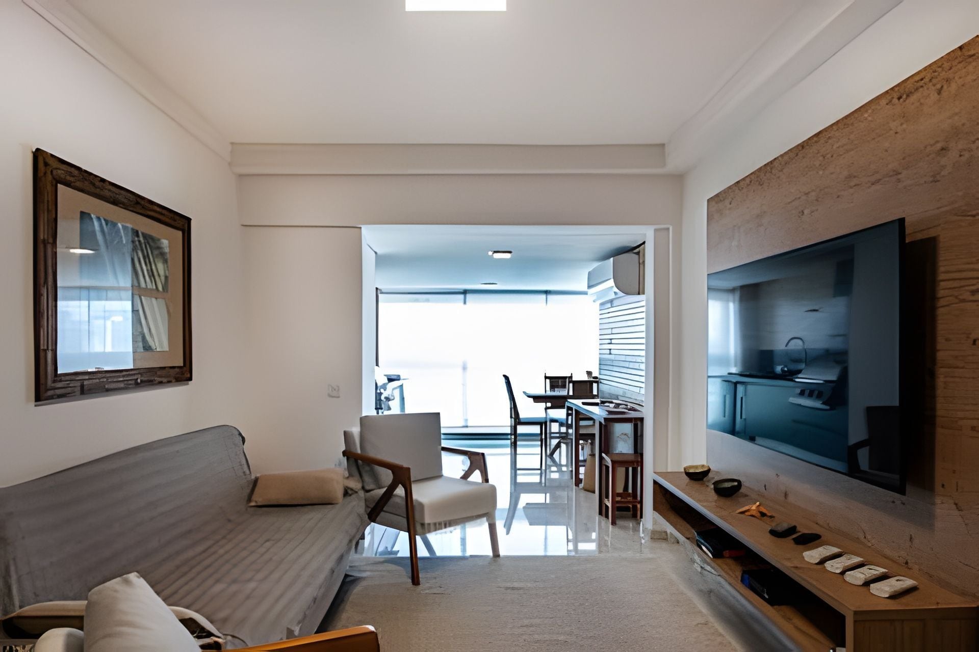 Una sala moderna con un sofá, sillas, un comedor y una cocina visible a través de una puerta abierta.