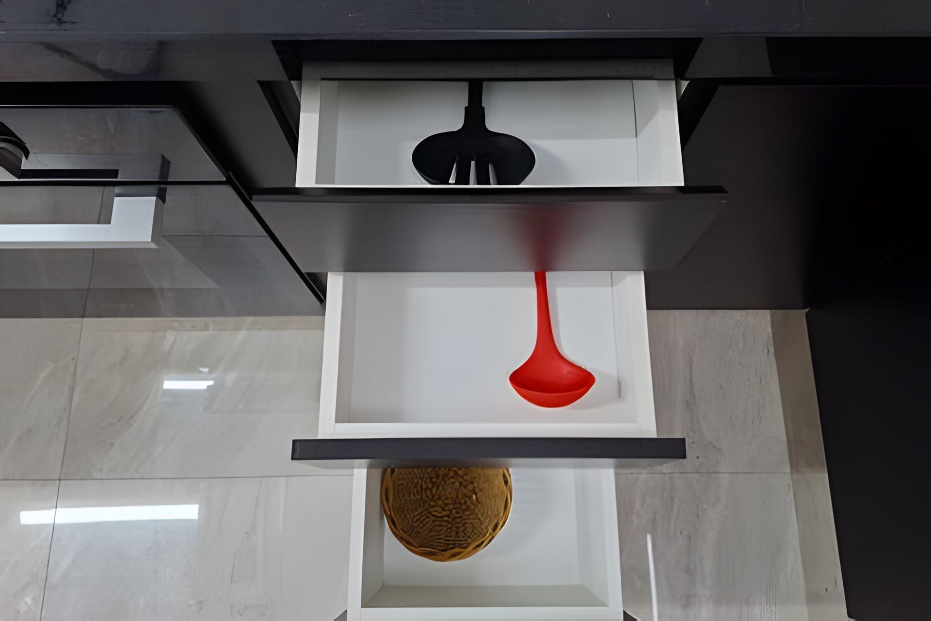 Un interior moderno con una paleta de colores blanco y negro, destacando un objeto rojo sobre una estantería blanca y un artículo marrón texturizado en otra.