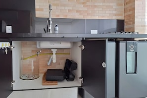 A kitchen with a built-in sink, a water filtration system, and a compact refrigerator.