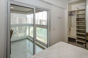 Ein Schlafzimmer mit einer Schiebetür zu einem Balkon, einem Bett mit einem gemusterten Matratze sowie einer eingebauten Regaleinrichtung, auf der sich eine Matratze befindet.