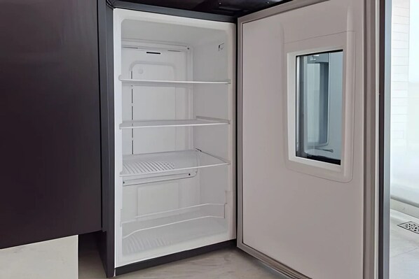 An interior view of a refrigerator with multiple shelves and a small window on the door.