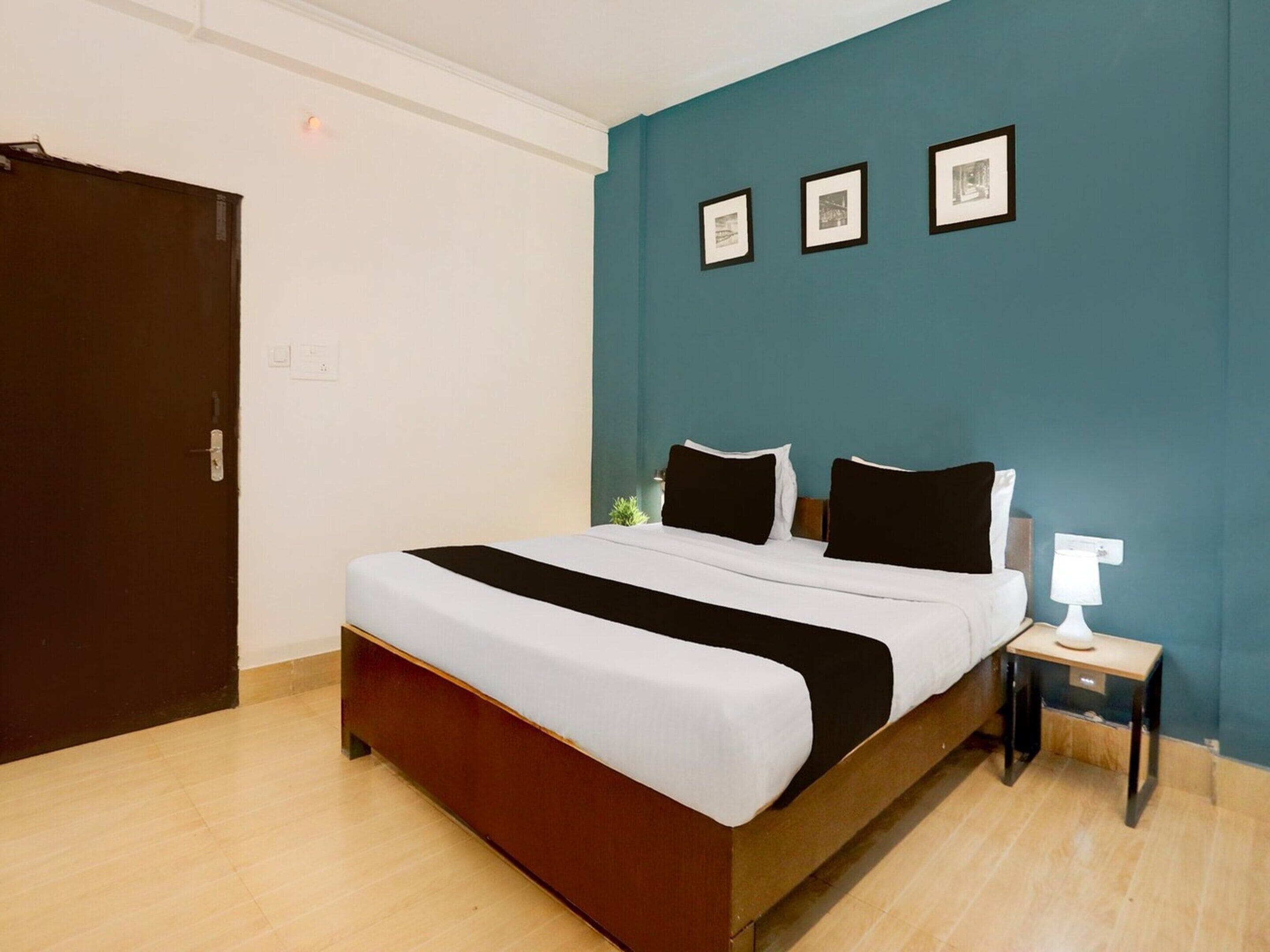 Una camera d'albergo con un letto, un comodino, una lampada e tre quadri appesi al muro.