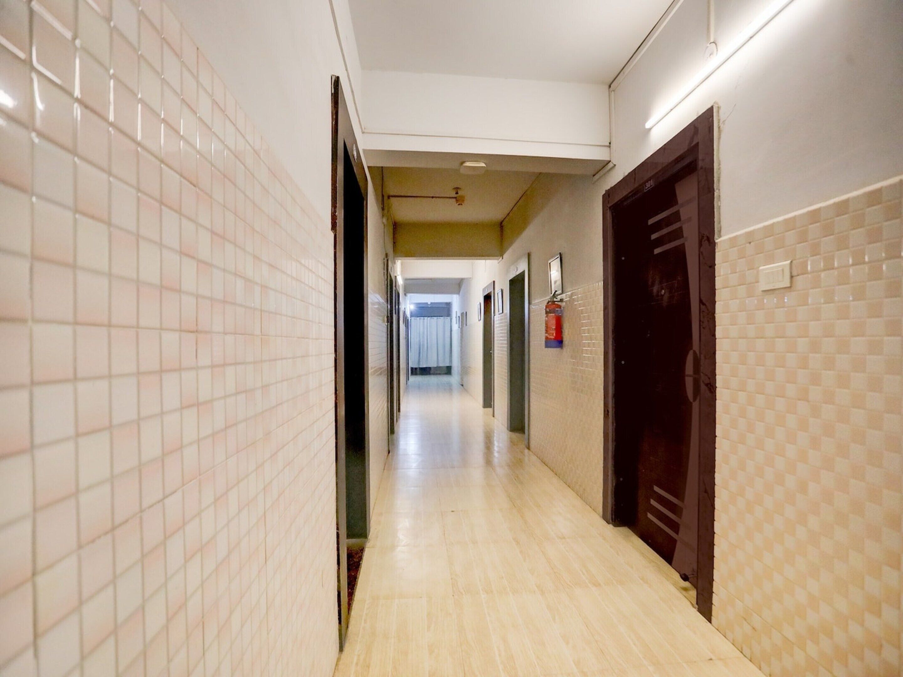 Un pasillo de hotel con paredes de azulejos, suelo de madera y puertas que dan a las habitaciones.
