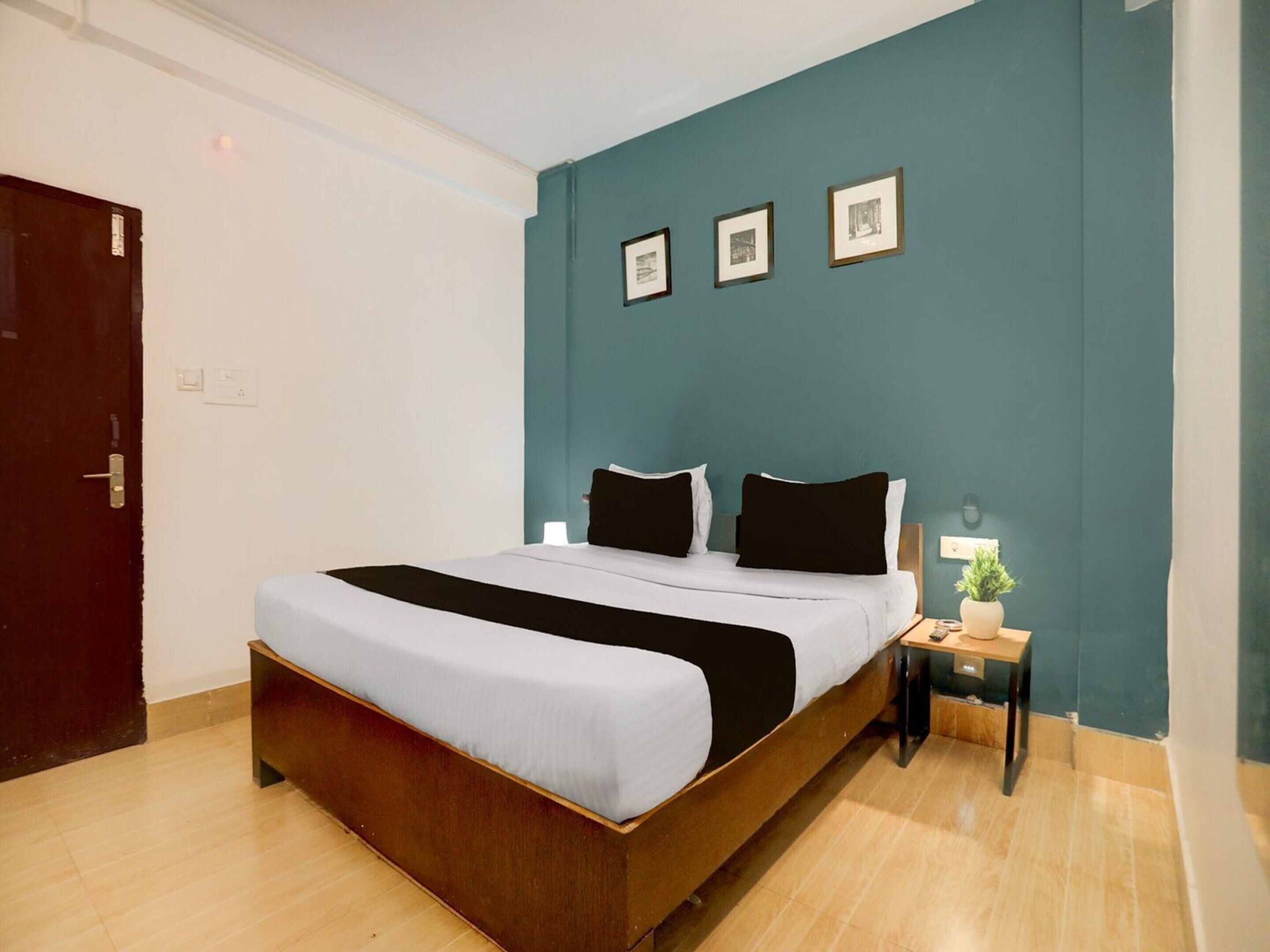 Ein Hotelzimmer mit einem Bett, einem Nachttisch, einer Lampe und einer Tür.