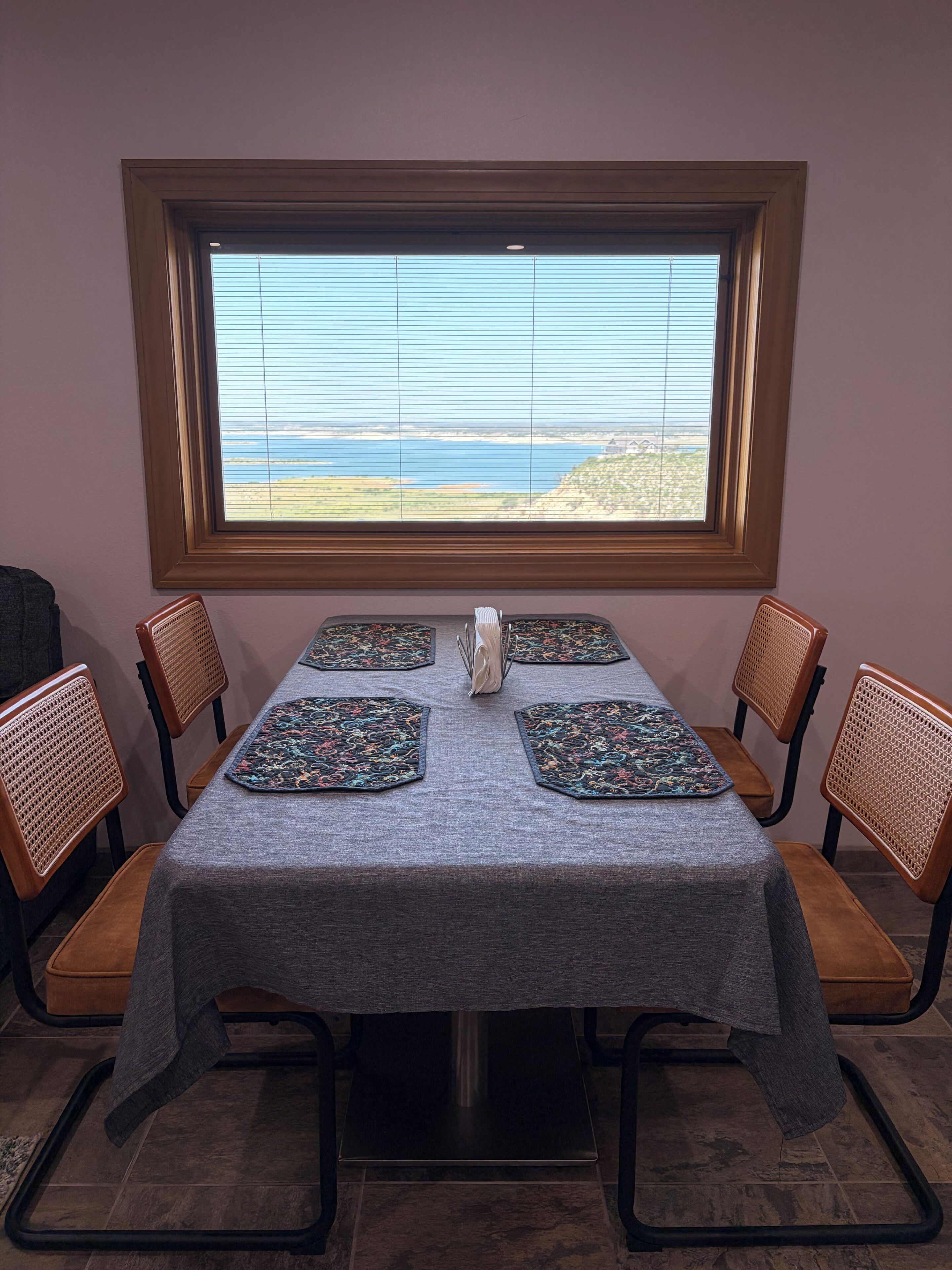 A dining table with a view of the ocean through a window.