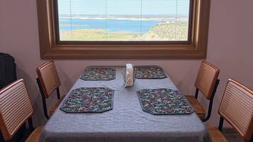 A dining table with a view of the ocean through a window.