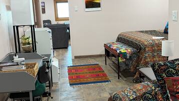 A hotel room with a desk, two beds, a colorful rug, and a poster on the wall.