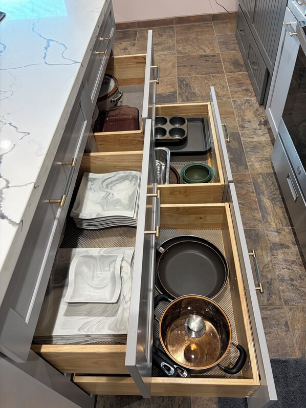 A kitchen with a marble countertop, a drawer organizer with utensils, and a stove.