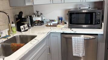 A modern kitchen with stainless steel appliances, grey cabinetry, and a tiled backsplash.