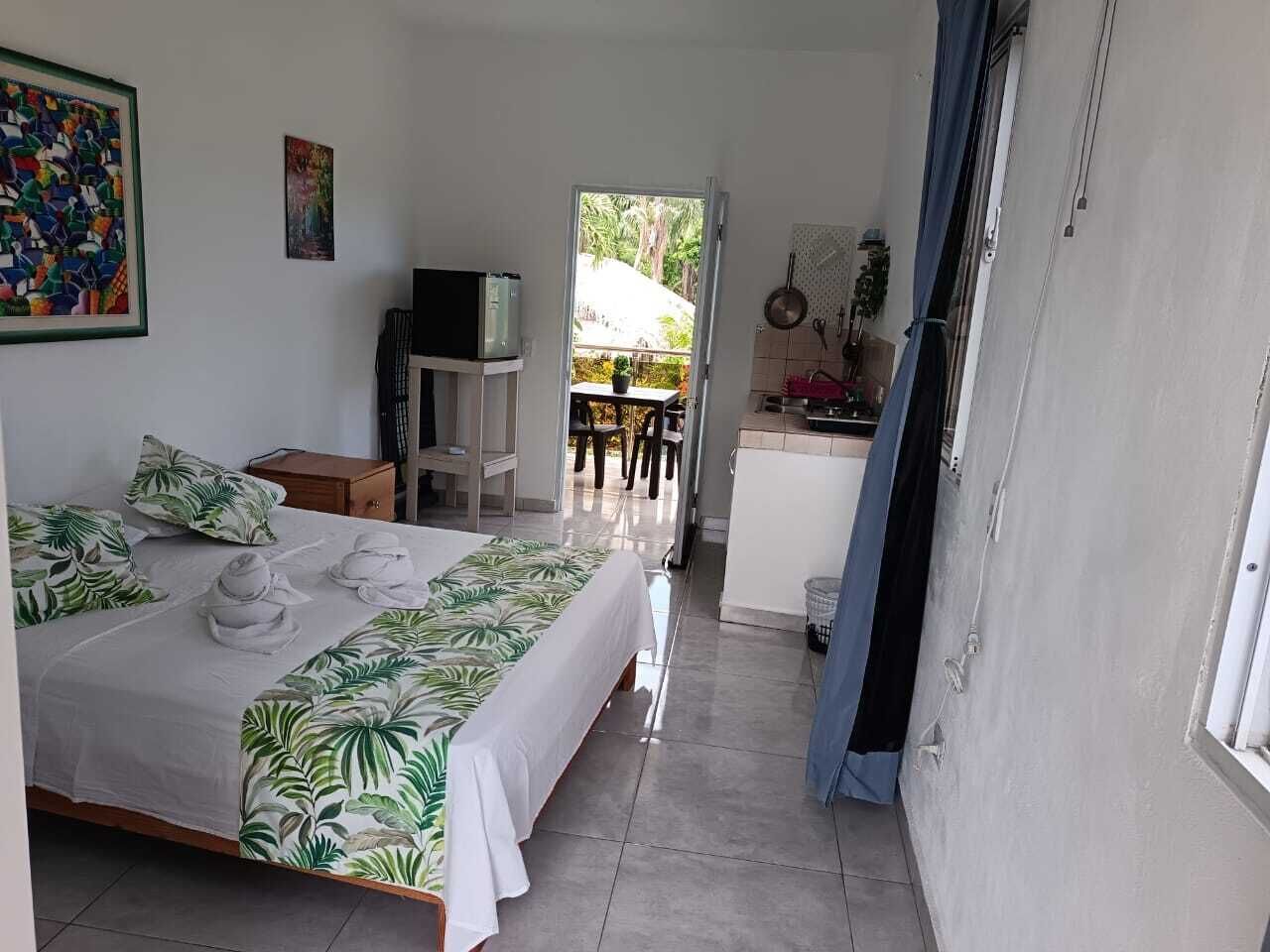 A hotel room with a bed, a desk, and a view of the outdoor area.