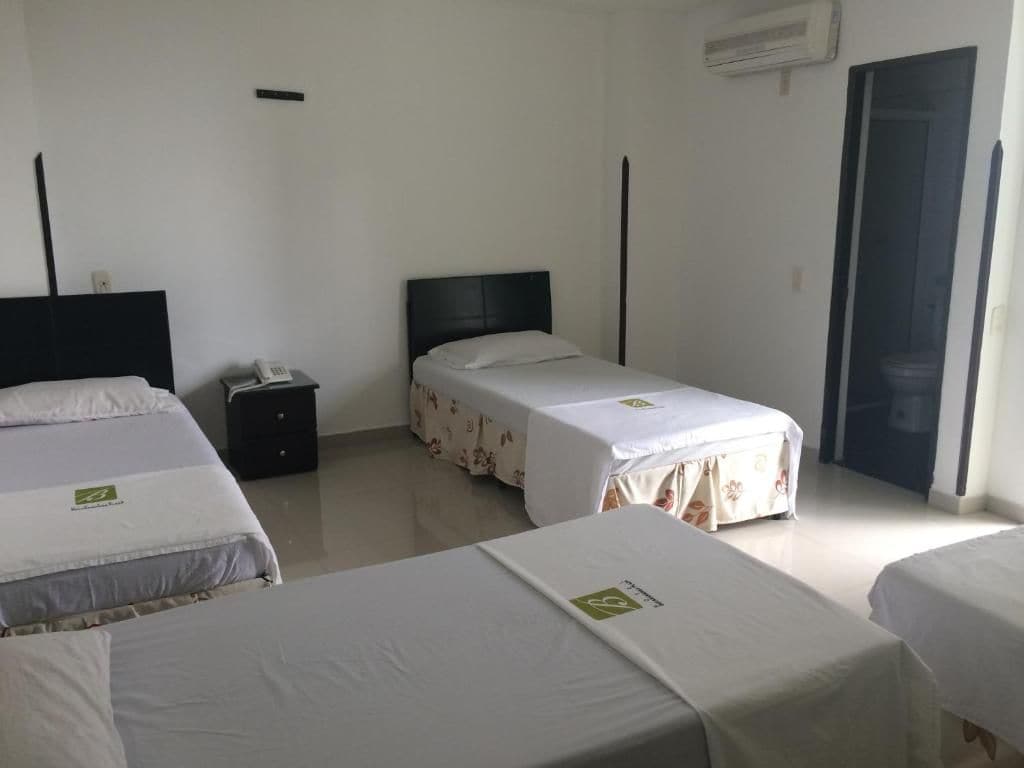 A hotel room with two beds, a nightstand, and a door.