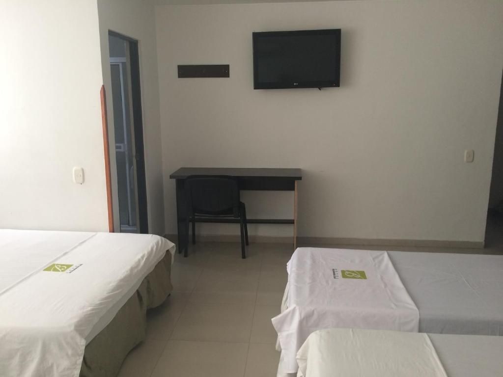 A hotel room with two beds, a desk, and a television.