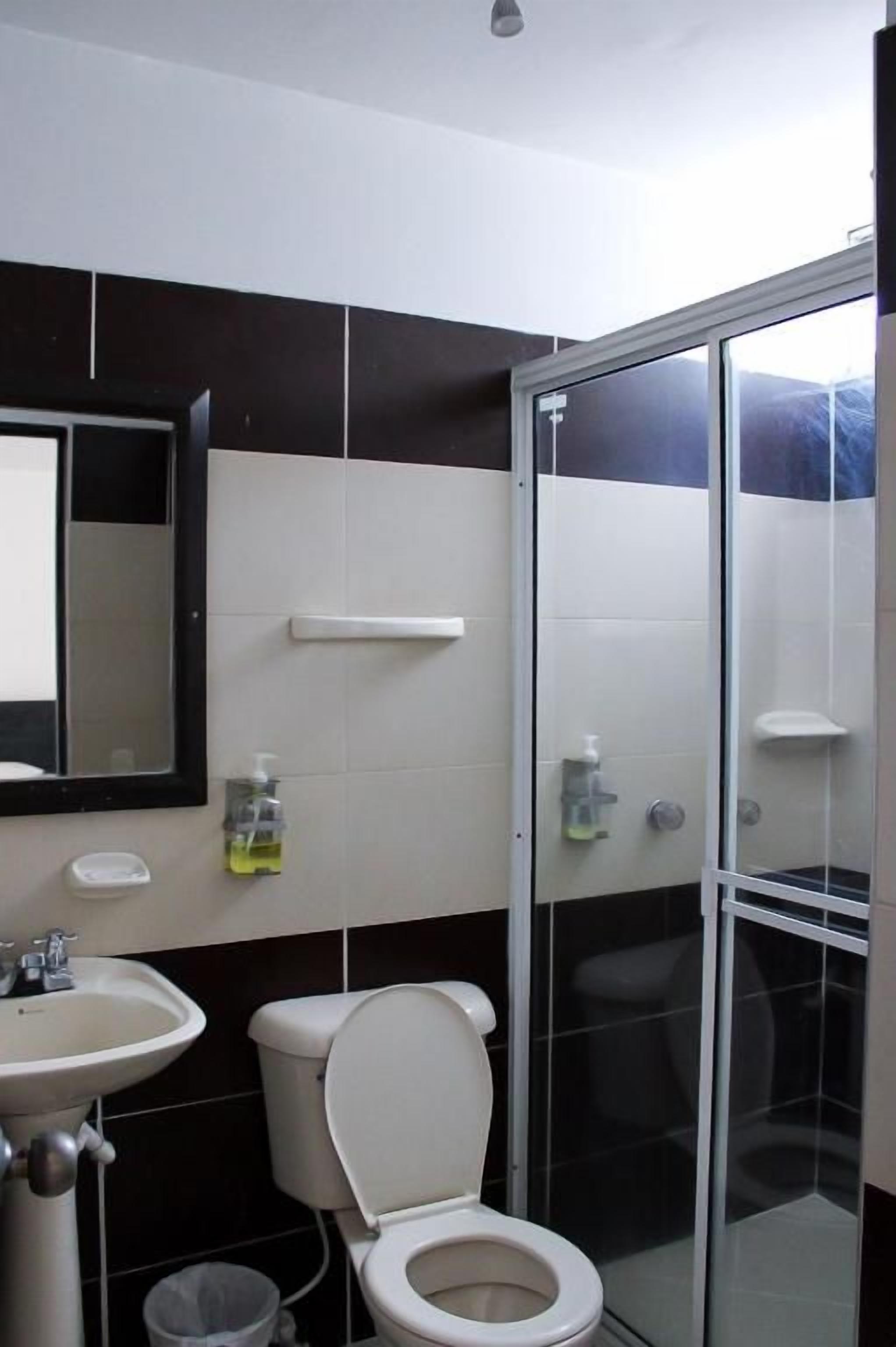 Un baño con inodoro, lavamanos y cabina de ducha de vidrio.