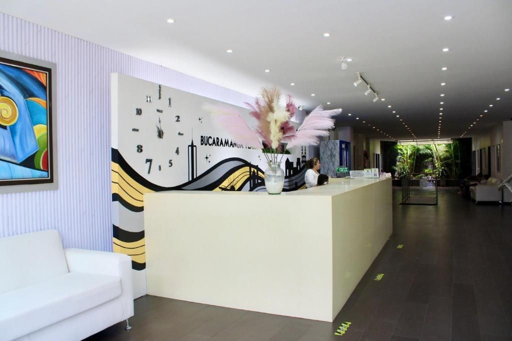 A reception area with a white reception desk, a clock, and a painting on the wall.