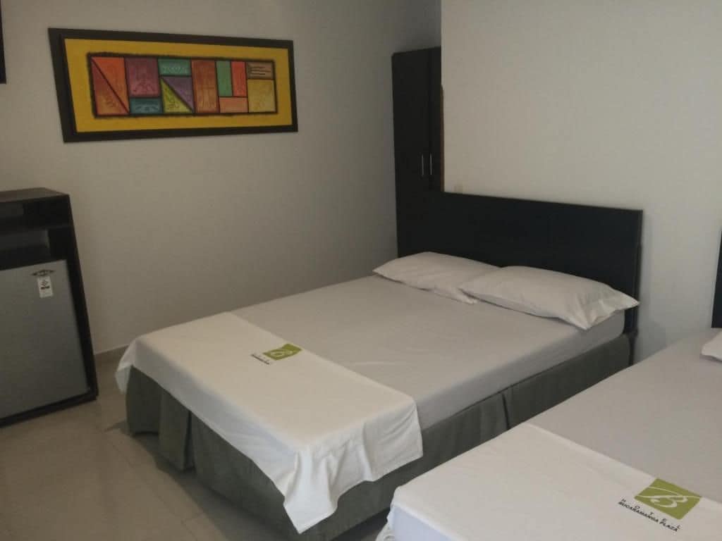 A single-bed room with a headboard, a bedside table, and a framed artwork on the wall.