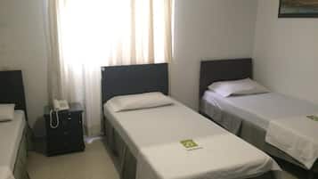 A hotel room with two single beds, a bedside table with a phone, and a window with curtains.