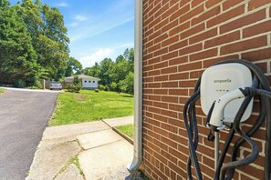 A brick wall with an electric vehicle charging station labeled 'emporía' and a driveway leading to a house. - 3BR Home Near BeltLine (Atlanta)