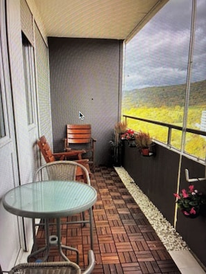 Une terrasse couverte avec une table et des chaises, un banc et des plantes en pot.
