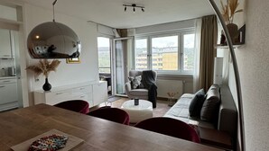 A modern living room with a dining area, a large window, and a ceiling light fixture. - Stylish flat close to Basel with a stunning view (Weil am Rhein)