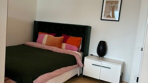 A bedroom with a bed, bedside table, and a framed picture on the wall. - Stylish flat close to Basel with a stunning view (Weil am Rhein)