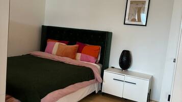 A bedroom with a bed, bedside table, and a framed picture on the wall.