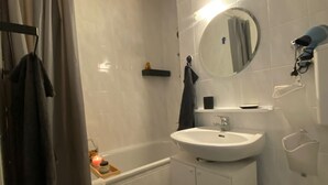 A modern bathroom with a bathtub, a sink, a mirror, and a toilet. - Stylish flat close to Basel with a stunning view (Weil am Rhein)