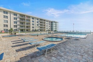A hotel with multiple balconies, a swimming pool, and lounge chairs. - 🏖️ Beachfront | Ocean Views | Sea Coast Gardens III 216 🏖️ (New Smyrna Beach)
